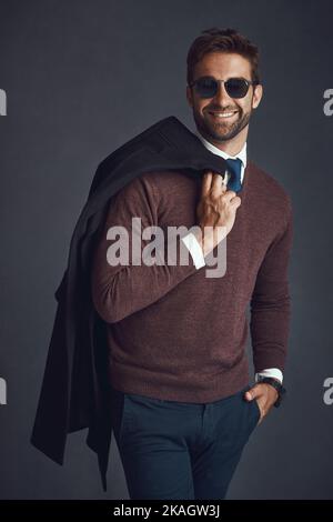Fashion fit für den modernen Mann. Studioporträt eines stilvoll gekleideten jungen Mannes, der seine Jacke vor einem grauen Hintergrund trägt. Stockfoto