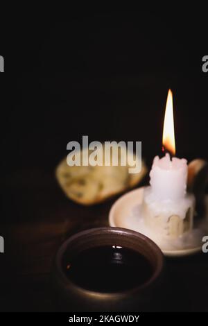 Heilige Kommunion symbolisiert Blut und Fleisch Jesu Christi Letztes Abendmahl Wein, Brot und eine hell leuchtende Kerze auf dem Kerzenständer Stockfoto