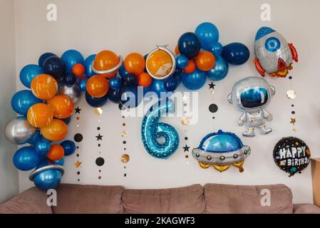 Geburtstagsdekor im Stil des Kosmos. Luftballons und die Zahl 6 an der Wand Stockfoto