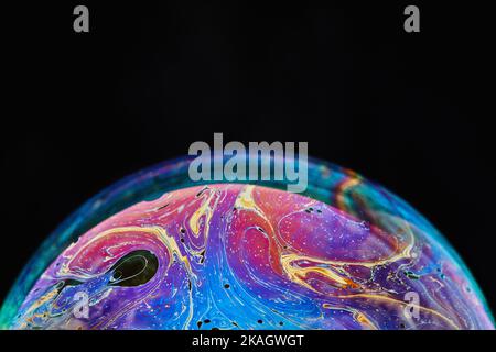 Virtual Reality Raum mit abstrakten multicolor psychedelischen Planeten. Nahaufnahme Seifenblase wie ein außerirdischer Planet auf schwarzem Hintergrund Stockfoto