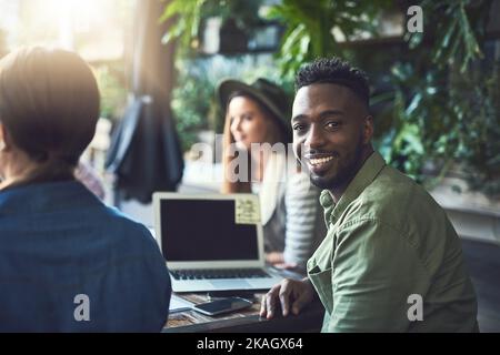 Wir lieben die lockere Atmosphäre in diesem Café. Porträt eines jungen Designers, der sich in einem Café mit seinen Kollegen trifft. Stockfoto