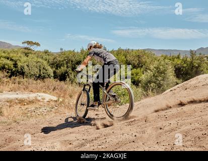 Fahrrad, Natur und Sportler auf einem Feldweg für ein Outdoor-Abenteuer, eine Reise oder ein Training. Fahrrad, Sport und Mann Radfahren auf Off-Road in einem Feld für Stockfoto