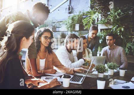Stickige Sitzungen in den Sitzungssäle, nicht für dieses Team. Ein Team von Kollegen, die während einer Sitzung in einem Café im Freien einen Laptop zusammen benutzen. Stockfoto