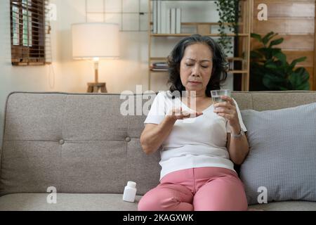 Ältere kranke Frau halten Pillen in der Hand Gießen Kapseln aus Medikamentenflasche nehmen Schmerzmittel Ergänzung Medizin, alte ältere Menschen Stockfoto