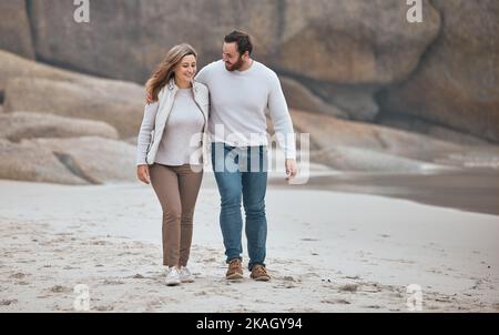 Glückliches Paar am Strand, Wandern während Datum und Reise, Urlaub zusammen mit Liebe und Pflege im Freien. Liebe, Mann und Frau lächeln auf einem romantischen Spaziergang mit Stockfoto