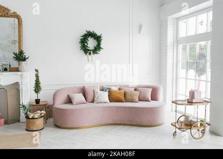 Stilvolles rosa Sofa in einem klassischen Wohnzimmer mit französischen Fenstern, dekoriert für Weihnachten und Neujahr Stockfoto
