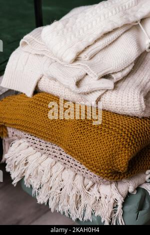 Damenkleider mit Strickpullover oder Plaids aus Wolle. Verschiedene Strickmuster, gestapelt. Warm kuscheliges Konzept von Winter- und Herbststrickmode Stockfoto