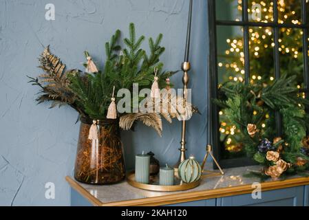 Weihnachtsdekor im Wohnzimmer, Christbaumzweige, Kerzen auf der blauen Kommode Stockfoto