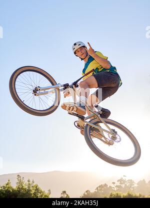 Fahrrad, springen und Felsen an der Hand Schild mit einem Mann bmx Fahrer springen über eine Rampe auf einem Trail oder Kurs in der Natur. Himmel, Berg und Radfahren mit einem Männchen Stockfoto