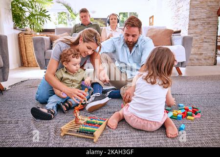 Familie, Spielzeug und Kinder spielen im Wohnzimmer zu Hause, Spaß haben und sich mit den Eltern. Liebe, Kinderentwicklung und Pflege der großen Familie, Opa und Stockfoto