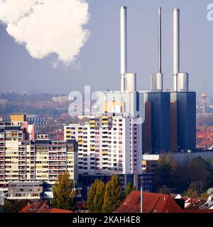 Türme und Kamine eines riesigen Blockheizkraftwerks hinter anonymen Wohnblöcken am Rande der Innenstadt von Hannover Stockfoto