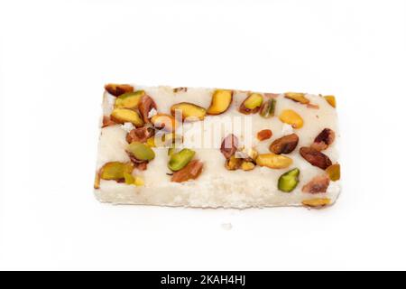 Ein Stück weiche Kokosnuss ägyptischen Süßigkeiten mit Pistazien bedeckt, ägyptische kulturelle Desserts des Propheten Muhammad Geburt Feier (mallid halawa), fest Stockfoto