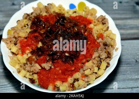 Koshary Teller, ägyptische sehr beliebt und traditionelle Küche von Reis mit braunen Linsen, Kichererbsen, Makkaroni, gekrönt mit Tomaten-Chili-Sauce und knusprig Stockfoto