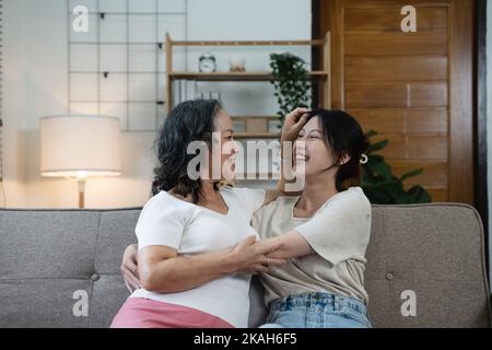 Lächelnd Erwachsene Tochter umarmt ältere Mutter. Zwei Generationen Konzept, schöne junge Frau umarmt reife Frau, posiert für Foto zusammen. Stockfoto