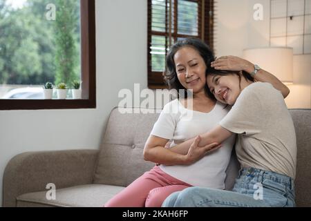 Lächelnd Erwachsene Tochter umarmt ältere Mutter. Zwei Generationen Konzept, schöne junge Frau umarmt reife Frau, posiert für Foto zusammen. Stockfoto