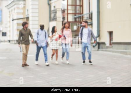 Verschwommenes Bild von Studenten plaudern fröhlich, während sie die Straße entlang gehen. Stockfoto