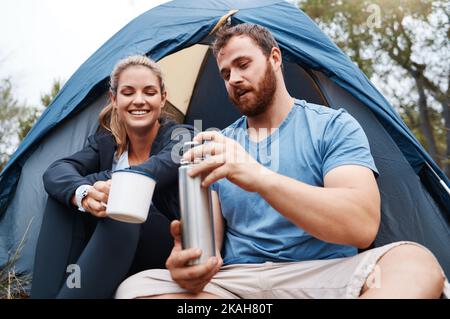 Camping, Zelt und Paar mit Kaffee am Morgen, genießen Sie die Natur und Urlaub im Freien. Freiheit, Reisen und Mann mit Kolben gießt heißes Getränk Stockfoto