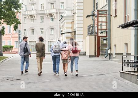 Eine Gruppe junger Leute, die sich lustig unterhalten und die Straße entlang gehen. Stockfoto