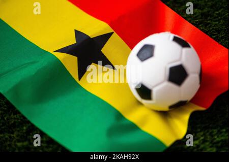 Ghanaische Fußballnationalmannschaft. Nationalflagge auf grünem Gras und Fußball. Fußball-Wallpaper für Meisterschaft und Turnier im Jahr 2022. Internationale Welt Stockfoto