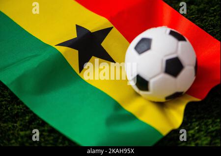 Ghanaische Fußballnationalmannschaft. Nationalflagge auf grünem Gras und Fußball. Fußball-Wallpaper für Meisterschaft und Turnier im Jahr 2022. Internationale Welt Stockfoto