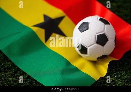 Ghanaische Fußballnationalmannschaft. Nationalflagge auf grünem Gras und Fußball. Fußball-Wallpaper für Meisterschaft und Turnier im Jahr 2022. Internationale Welt Stockfoto