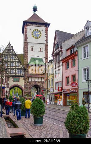 Straßenszene voller Touristen, Bürger und Fußgänger, Oberlinden gegenüber dem Schwäbischen Tor, historische Altstadt von Freiburg im Breisgau, Deutschland. Stockfoto