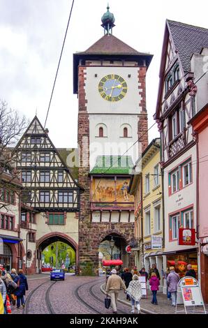 Straßenszene voller Touristen, Bürger und Fußgänger, Oberlinden gegenüber dem Schwäbischen Tor, historische Altstadt von Freiburg im Breisgau, Deutschland. Stockfoto