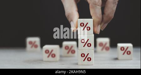 Konzept der Zinssätze für Finanzen und Hypothekenzinsen. Hand, um den Holzwürfelblock oben mit dem Symbol prozentuale Richtung nach oben zu bewegen Stockfoto