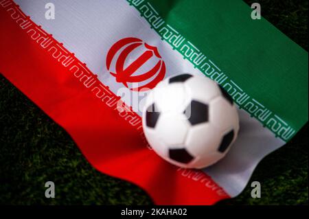 Iranische Fußballnationalmannschaft. Nationalflagge auf grünem Gras und Fußball. Fußball-Wallpaper für Meisterschaft und Turnier im Jahr 2022. Internationale Welt Stockfoto