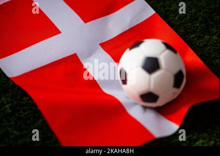 Dänische Fußballnationalmannschaft. Nationalflagge auf grünem Gras und Fußball. Fußball-Wallpaper für Meisterschaft und Turnier im Jahr 2022. Internationaler Praktikant Stockfoto