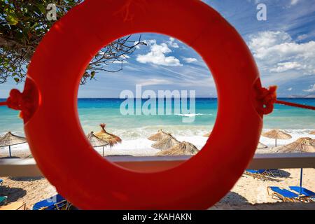 Mediterrane Motive und Stillleben. Blick auf den Strand durch den orangefarbenen Rettungsring. Albanische Riviera. Postkarten aus dem Mittelmeer. Stockfoto