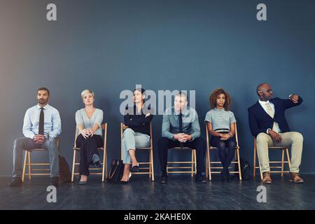 Sogar das Warten ist ein Interview vor dem Test. Eine Gruppe gut gekleideter Geschäftsleute saß in der Schlange, während sie darauf wartete, ein Interview zu werden. Stockfoto