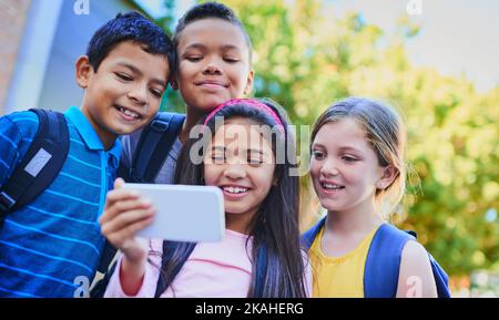 Wir müssen jeden Moment in diesem Alter festhalten. Eine vielfältige Gruppe von Kindern, die draußen ein Selfie machen. Stockfoto