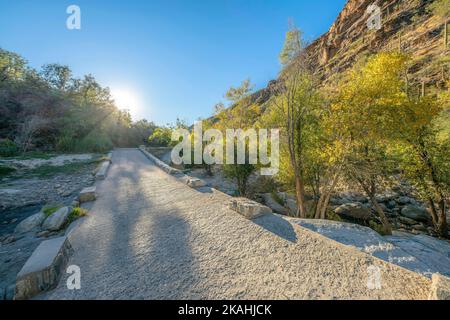 Gepflasterter Wanderweg entlang zerklüfteter Klippen im Sabino Canyon Arizona. Wanderweg für Wanderer in der malerischen State Park Erholungsgebiet mit blauen sk Stockfoto