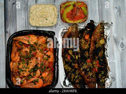 Meeresfrüchteküche mit gekochten Garnelen gemischter Knoblauch, Zitrone, Petersilie, Pfeffer, Zwiebel und Tomaten und Holzkohle gegrillter Meerbarsch mit Petersilie und t Stockfoto