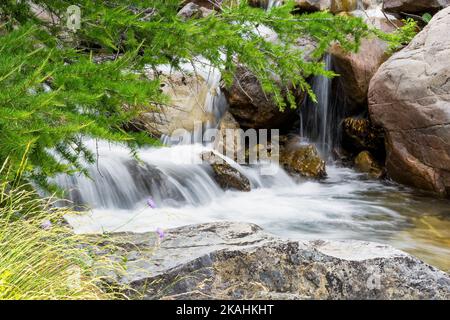 An heißen Sommertagen bietet sich ein schöner Blick auf den Wasserfall und die Felsen im Nationalpark Mercantour in den französischen Alpen Stockfoto