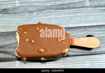 Eis mit reichhaltigem Vanillegeschmack in knackiger brauner Milchschokolade und gerösteter Mandel isoliert, Vanilleeis-Stick beschichtet und mit einer Schicht bedeckt Stockfoto