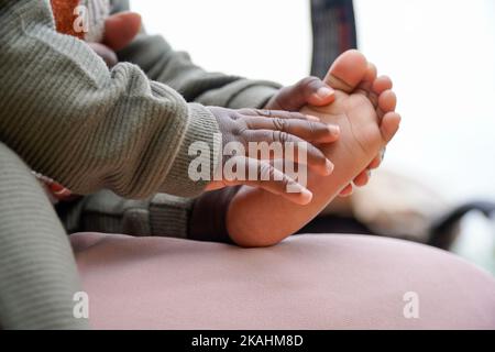 Fuß und Hände eines schwarzen afrikanischen Babys, das spielt Stockfoto