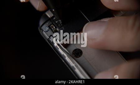 Smartphone-Hersteller oder -Ingenieur untersucht die Rückseite eines Smartphones, extreme Nahaufnahme, Smartphone-Reparatur oder Fertigungskonzept Stockfoto