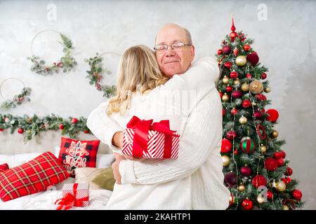 weihnachten, Feiertage und Menschen Konzept - glückliches Paar in santa Hüte Austausch von Geschenken zu Hause. Stockfoto