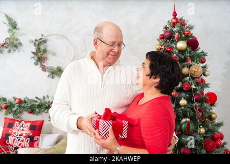Ehemann schenkte seiner Frau Weihnachtsgeschenk. Glückliches Paar mittleren Alters zu weihnachten Stockfoto
