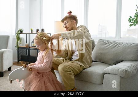 Vater mit verrückter Frisur macht Haare für Tochter Stockfoto