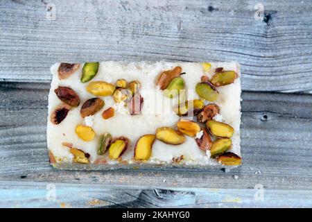 Ein Stück weiche Kokosnuss ägyptischen Süßigkeiten mit Pistazien bedeckt, ägyptische kulturelle Desserts des Propheten Muhammad Geburt Feier (mallid halawa), fest Stockfoto