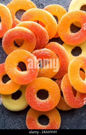 Ein Stapel von knallbunten, mit Pfirsich aromatisierten, mit Zucker überzogenen Gummiringen. Stockfoto