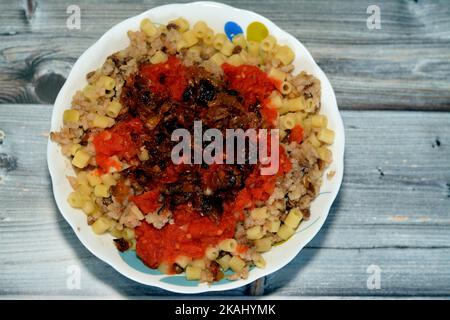 Koshary Teller, ägyptische sehr beliebt und traditionelle Küche von Reis mit braunen Linsen, Kichererbsen, Makkaroni, gekrönt mit Tomaten-Chili-Sauce und knusprig Stockfoto