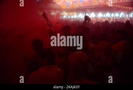 Indische hinduistische Anhänger werfen während des Laths mar Holi in Barsana, etwa 43 km von Mathura entfernt, am 17,2016. März farbigen Pulver im Radha Rani Tempel ab.während des Lathmar holi Festivals greifen Frauen von Barsana, der legendären Heimatstadt Radha, Consort des Hindu Lord Krishna, die Männer aus Nandgaon an, Die Heimatstadt von Lord Krishna, mit Holzstäben als Reaktion auf ihre Bemühungen, Farbe auf sie zu legen. Stockfoto