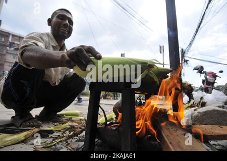 Pashupati Khatri, 45 Jahre alt, ständiger Bewohner von Ramechhap, lächelt, als er am 1. Juni 2016 mit Hilfe des Holzfeuers in Kathmandu Mais röstet. Er verwendete Rohmais bei NRS kaufen. 15 (0,15 US-Dollar) pro Stück und verkaufte es dann nach dem Rösten zu 25 (0,25 US-Dollar) pro Stück, und er pflegte NRS zu verdienen. 500 (5,00 US-Dollar) pro Tag. (Foto von Narayan Maharjan/NurPhoto) *** Bitte nutzen Sie die Gutschrift aus dem Kreditfeld *** Stockfoto