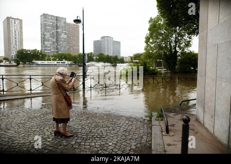 Die Menschen machen Fotos und beobachten, wie das Wasser in der Nähe des Eiffelturms aufsteigt, während die Böschungen des Flusses seine nach vier Tagen starken Regens am 3. Juni 2016 in Paris, Frankreich, überströmen. Nordfrankreich erlebt derzeit Regenwetter und verursacht Überschwemmungen in Teilen Frankreichs, insbesondere in Paris, wo die French Open Verzögerungen bei den Spielen hatten. (Foto von Mehdi Taamallah/NurPhoto) *** Bitte benutzen Sie die Gutschrift aus dem Kreditfeld *** Stockfoto