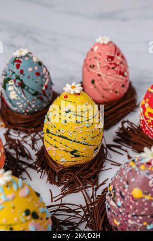 Die Schokoladen-ostereier in den Schokoladen-Trinkhalmen sind in verschiedenen Farben dekoriert Stockfoto