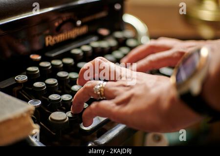 Nahaufnahme der Hände einer Frau, die in einem Vintage-Geschäft die Tasten einer antiken schwarzen Remington Schreibmaschine drückt Stockfoto